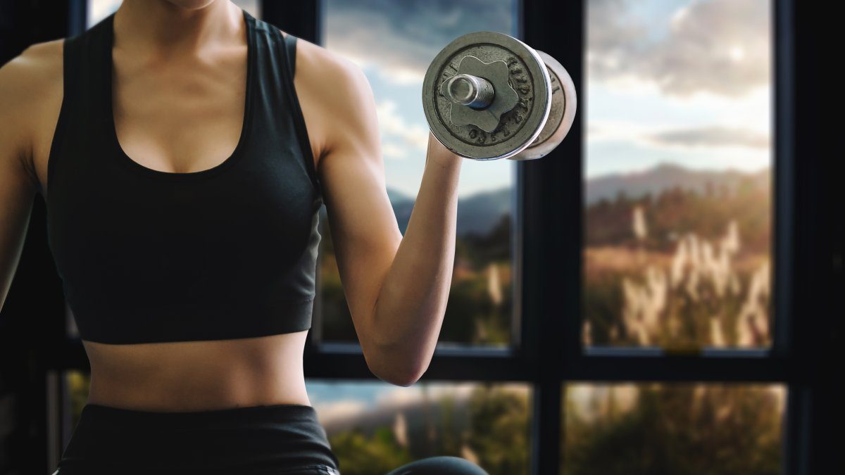 Kvinna tränar med hantlar hemma - Body for Life kombinerar träning och kost