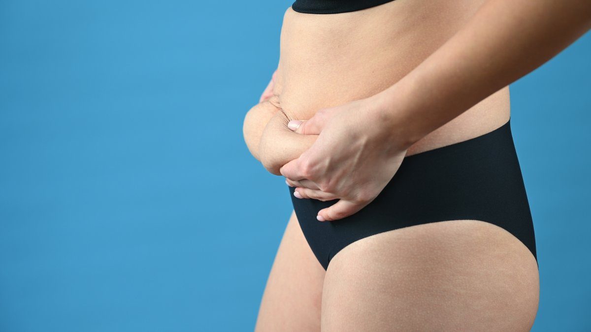 Kvinna som kontrollerar magfett - Flat Belly-dieten