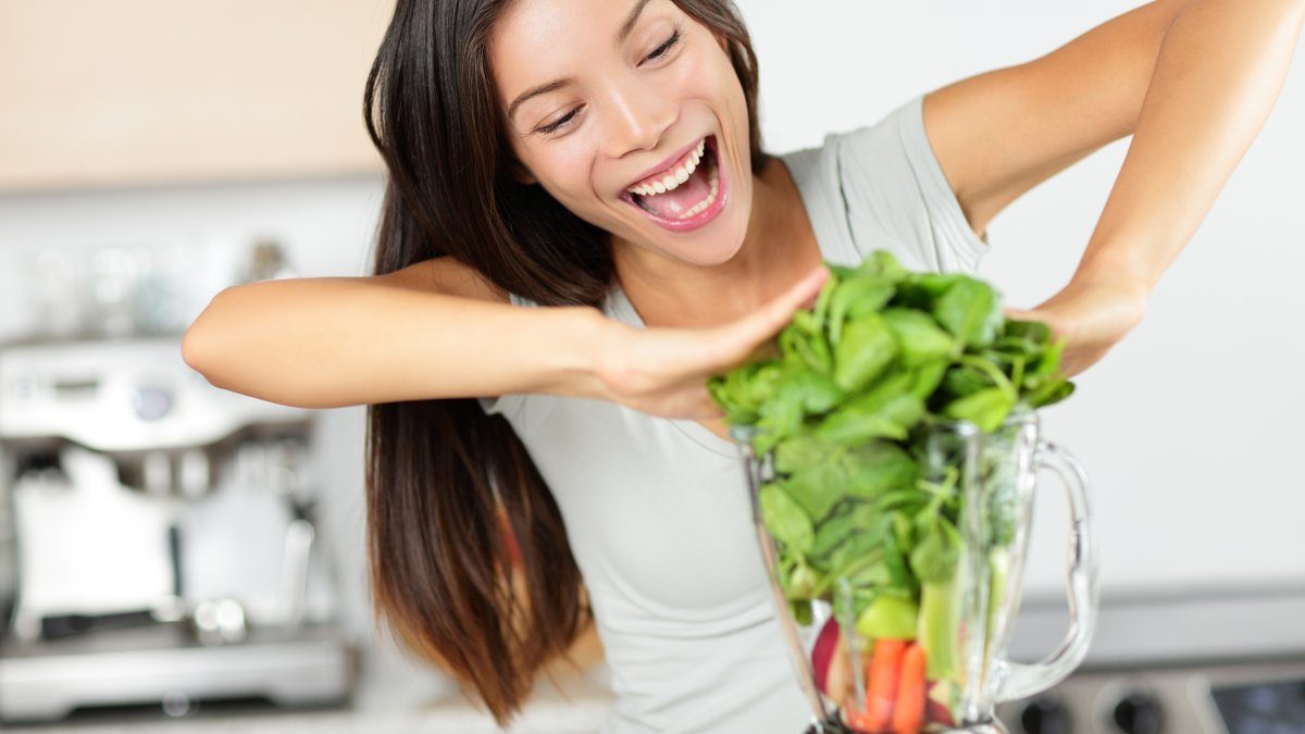 Kvinna gör grön smoothie - vegansk viktminskning med växtbaserad kost