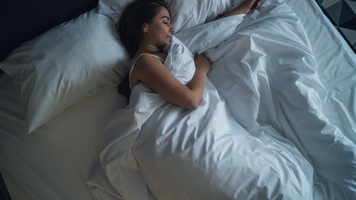 Kvinna sover i säng - sömnens roll för viktminskning