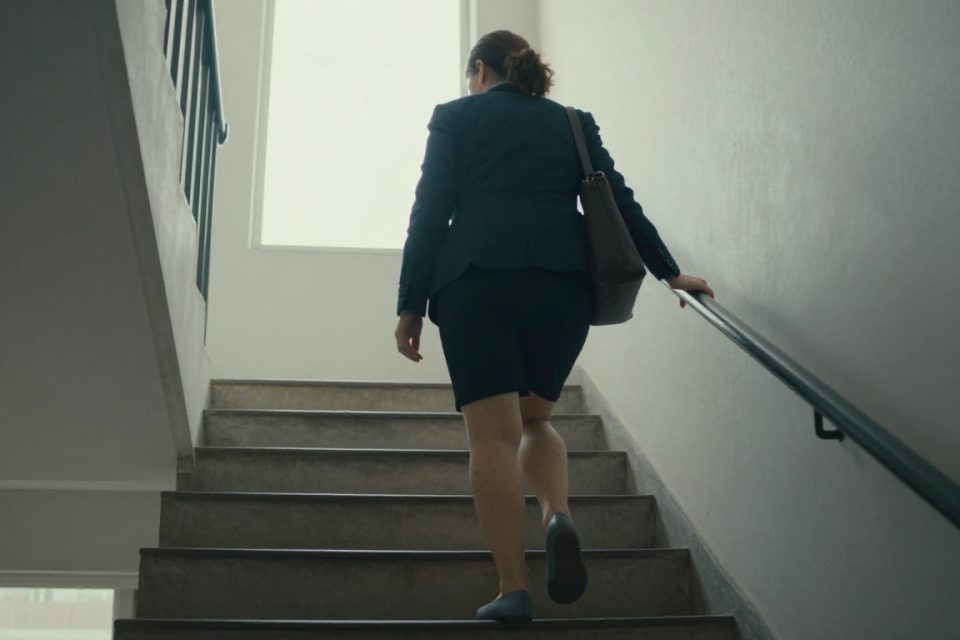 En kvinna i kontorskläder går uppför trapphuset i stället för att ta hissen, ett exempel på fler steg i vardagen.